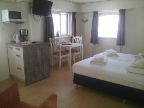 a room with a bed and a kitchen and a table at Hotel Rasch in Bergen aan Zee