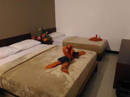 three beds in a room with orange towels on them at Bali Umah Tinjung in Tulamben