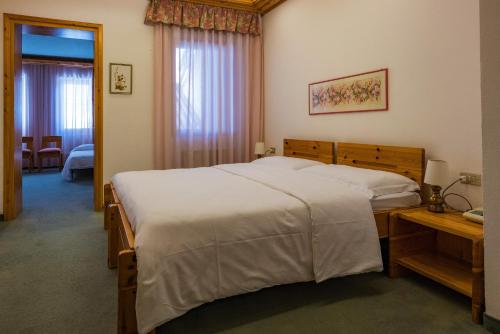 a bedroom with a large white bed and a table at Sporthotel Europa Sul Lago in Alleghe