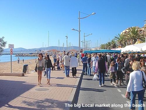 a crowd of people walking on a sidewalk near the beach at L'Oasis Hotel in Fréjus