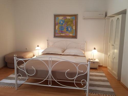 a white bed in a room with two lamps at Apartments Andrea in Šibenik