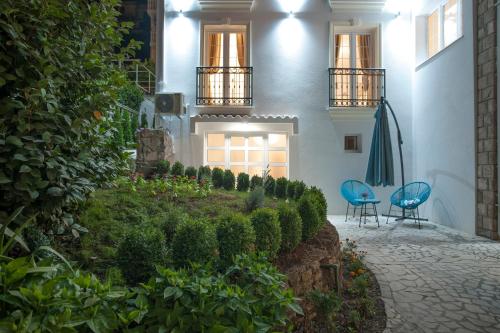 a house with two blue chairs and a garden at Apartments Captain's Villa in Budva