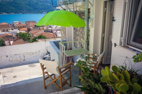 a green umbrella and chairs on a balcony with a view at Dolichi Studio in Samos