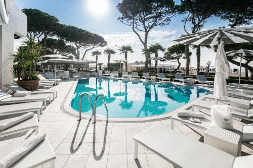 a swimming pool with chairs and an umbrella at Hotel Bellavista in Lignano Sabbiadoro
