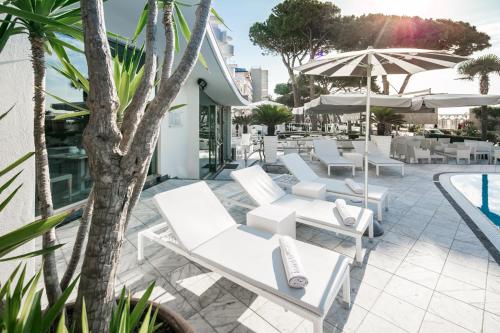 a group of white lounge chairs next to a pool at Hotel Bellavista in Lignano Sabbiadoro