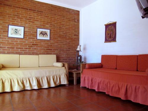 Habitación con 2 camas y pared de ladrillo en Costa Serrana Apart Hotel en Mina Clavero