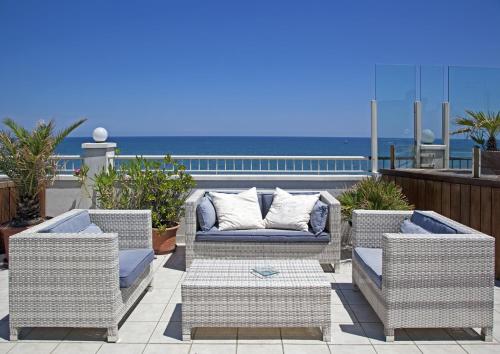 a patio with wicker chairs and a couch and the ocean at Hotel Ca' Bianca in Riccione