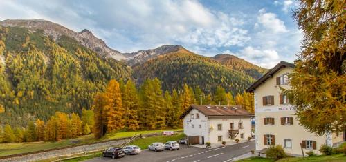 a group of cars parked in a parking lot in front of a mountain at Hotel Veduta in Cinuos-Chel