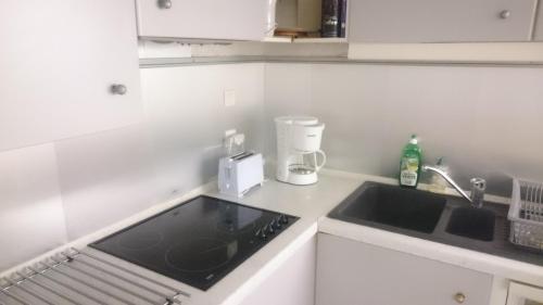 une cuisine blanche avec un évier et un plan de travail dans l'établissement Regina-Vignemale, à Cauterets