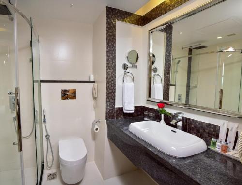 La salle de bains est pourvue d'un lavabo, de toilettes et d'un miroir. dans l'établissement The Central Residency, à Trivandrum