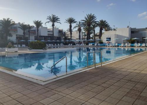 una grande piscina con palme e edifici di Residencial Primavera a Costa Del Silencio