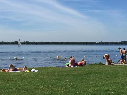 a group of people laying on the grass at a lake at Bed & Breakfast Kortenhoefsedijk in Kortenhoef