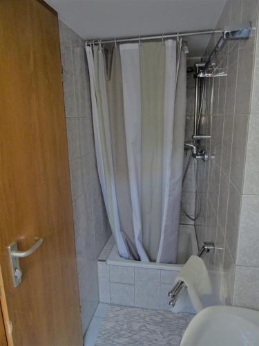 a bathroom with a shower with a white shower curtain at Alb Hotel Schalksburg in Albstadt