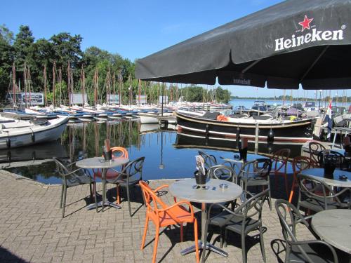 a restaurant with tables and chairs and boats in the water at Bed & Breakfast Kortenhoefsedijk in Kortenhoef