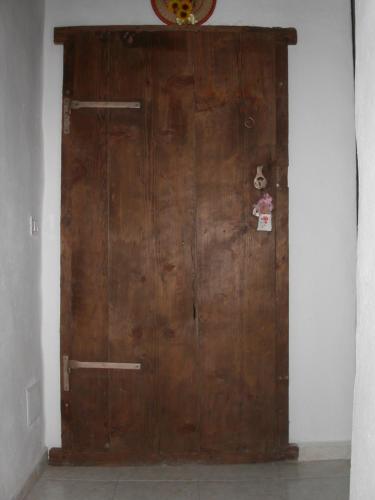 a large wooden door in the corner of a room at Locanda La Rosa in Pauli Arbarei