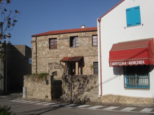 an old stone building with a red awning in front at Locanda La Rosa in Pauli Arbarei