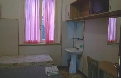 een kleine badkamer met roze gordijnen en een wastafel bij Hotel Parigi in Rimini