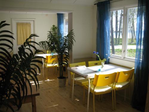 a dining room with yellow chairs and a table and a plant at Sikhall Camping in Sörbo