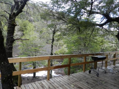 a grill on a wooden deck with a tree at Cabañas en Termas de Chillán in Recinto