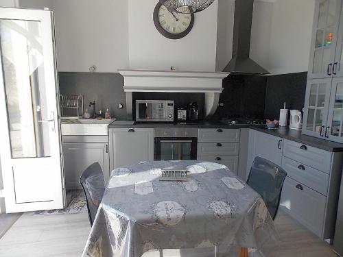 a kitchen with a table and a clock on the wall at Les Gîtes De Morville in Malaumont