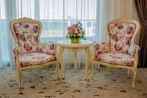dos sillas y una mesa con un jarrón de flores en Almar Luxury en Mamaia-Sat