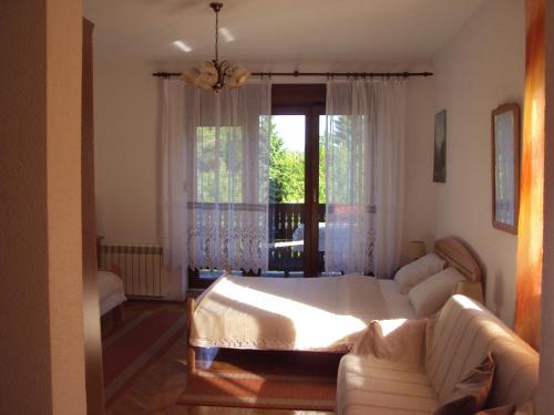 a bedroom with a bed and a couch and a window at PLITVICE KONAK Daic in Plitvička Jezera