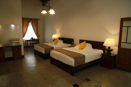 a hotel room with two beds and a desk at Thamaya Heritance Tangalle in Tangalle