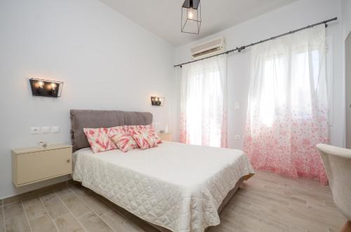 a white bedroom with a bed and a window at Filippa Studios in Plaka
