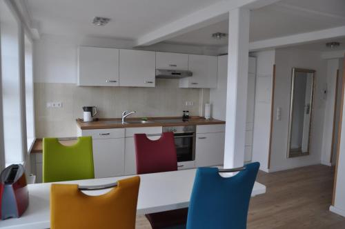a kitchen with white cabinets and colorful chairs at Hafenblick vom Kapitänshaus in Flensburg