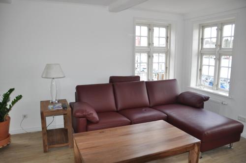 a living room with a brown couch and a table at Hafenblick vom Kapitänshaus in Flensburg