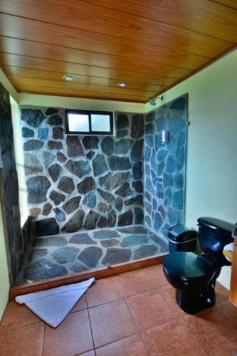a stone bathroom with a toilet and a stone wall at Rainbow Valley Lodge Costa Rica in Monteverde Costa Rica