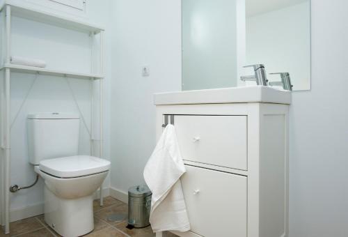a white bathroom with a toilet and a sink at Quintero Suites in San Bartolomé