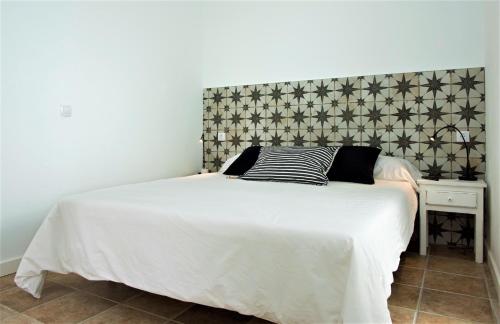 a bedroom with a white bed with a headboard at Quintero Suites in San Bartolomé