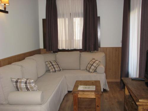a living room with a white couch and a coffee table at Aparthotel Sarrato in Sallent de Gállego