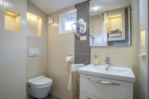 La salle de bains est pourvue d'un lavabo, de toilettes et d'un miroir. dans l'établissement Apartment Emilija, à Pula
