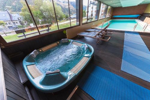 a hot tub in a room with a swimming pool at Aparthotel Sarrato in Sallent de Gállego