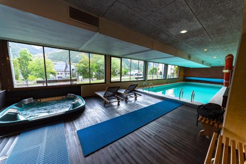 a pool room with a tub and a swimming pool at Aparthotel Sarrato in Sallent de Gállego