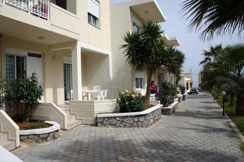 a walkway in front of a building with palm trees at Evilion hotel in Stalos