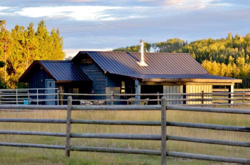 a blue barn with a fence in front of it at Woodhouse Cottages And Ranch in Prince George