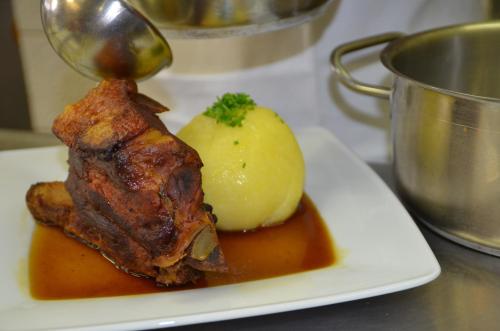 a white plate with a piece of meat and a potato at Hotel Königsteiner Hof in Königstein in der Oberpfalz