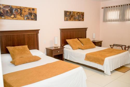 a bedroom with two beds and two tables and a painting at Allamanda Hotel in Port-au-Prince