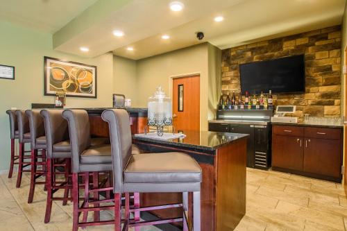 a bar with bar stools and a television at Cobblestone Hotel & Suites - Orrville in Orrville