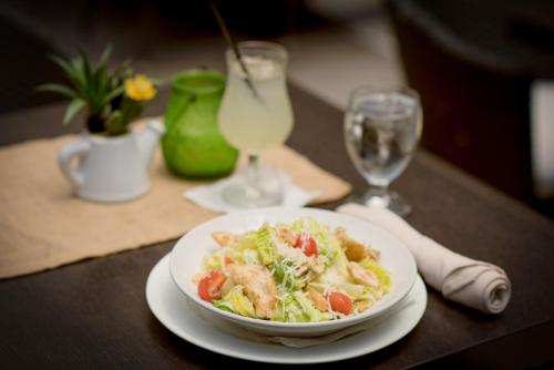 a plate of pasta and vegetables on a table with glasses at Allamanda Hotel in Port-au-Prince