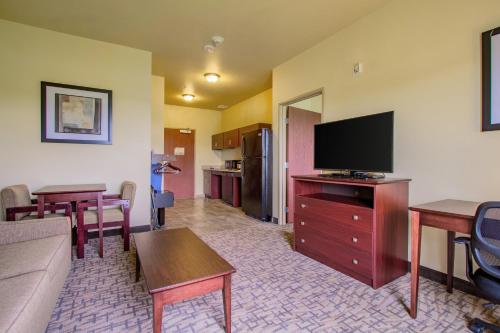 a living room with a couch and a flat screen tv at Cobblestone Hotel & Suites - Orrville in Orrville