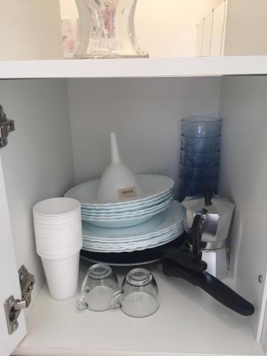 a shelf with a stack of plates and cups at San Domenico in Mola di Bari