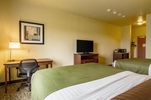 a hotel room with a bed and a desk and a television at Cobblestone Hotel & Suites - Orrville in Orrville