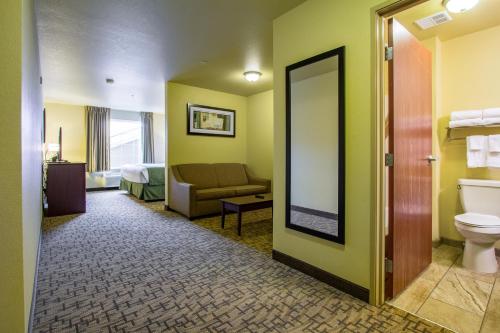 een hotelkamer met een toilet en een bank bij Cobblestone Hotel & Suites - Orrville in Orrville