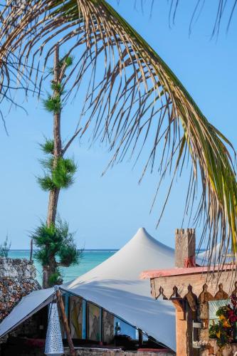 a tent and two palm trees on the beach at Seasons Lodge Zanzibar in Pongwe