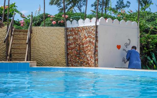 a man painting a wall next to a swimming pool at Seasons Lodge Zanzibar in Pongwe