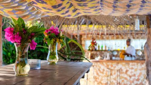 three vases with flowers sitting on a wooden table at Seasons Lodge Zanzibar in Pongwe